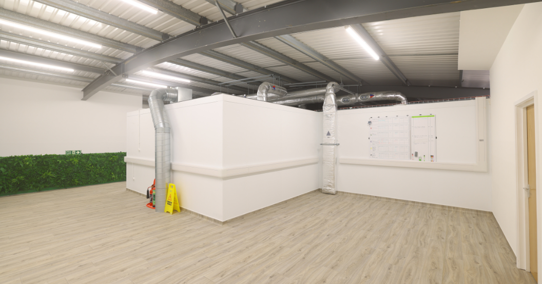 Modular cleanroom interior with wood-finish flooring, white wall panels and integrated cultivation or growth equipment area