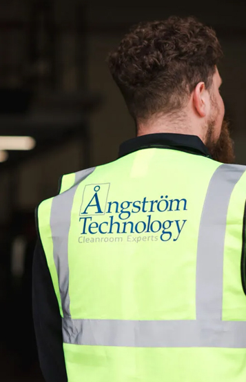 Angstrom Technology team member wearing branded safety vest on-site during cleanroom project delivery